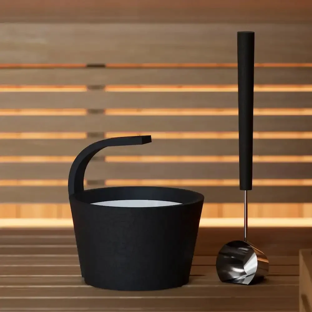 Black SAWO Dragonfire pail and ladle resting on a sauna bench