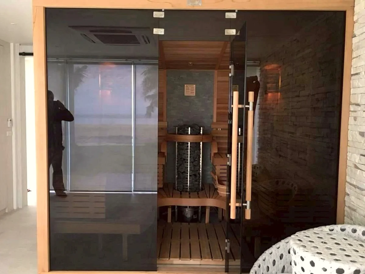 Indoor sauna with a smoked-glass front, tower heater visible inside