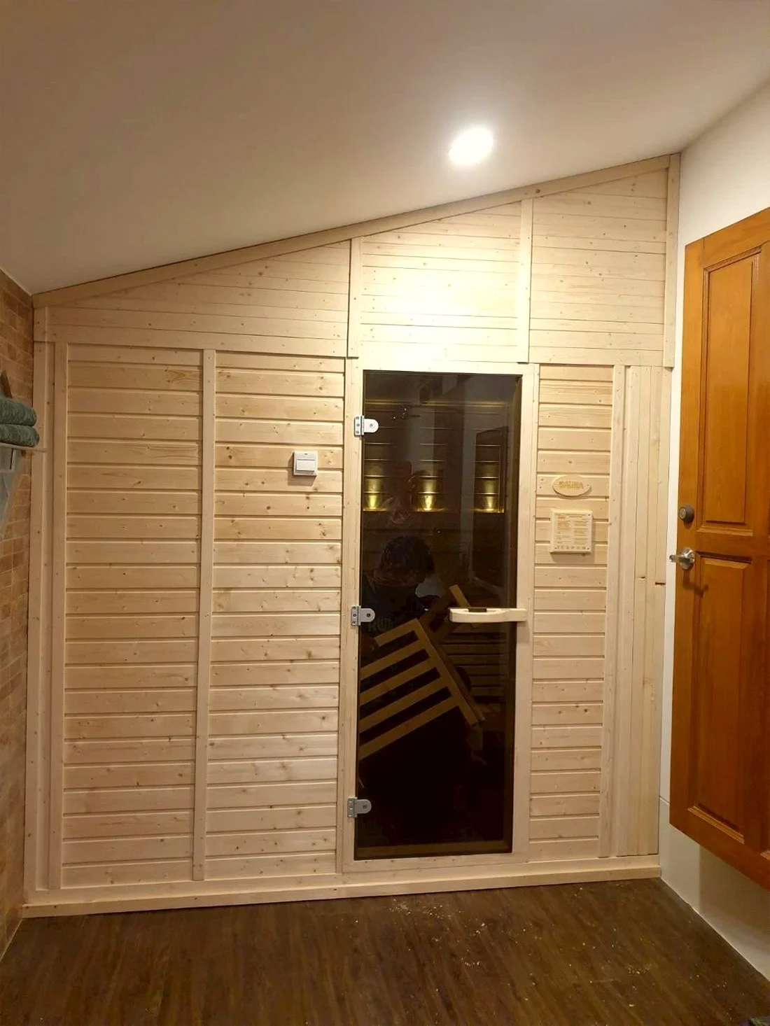 Pale-wood indoor sauna with a dark glass door